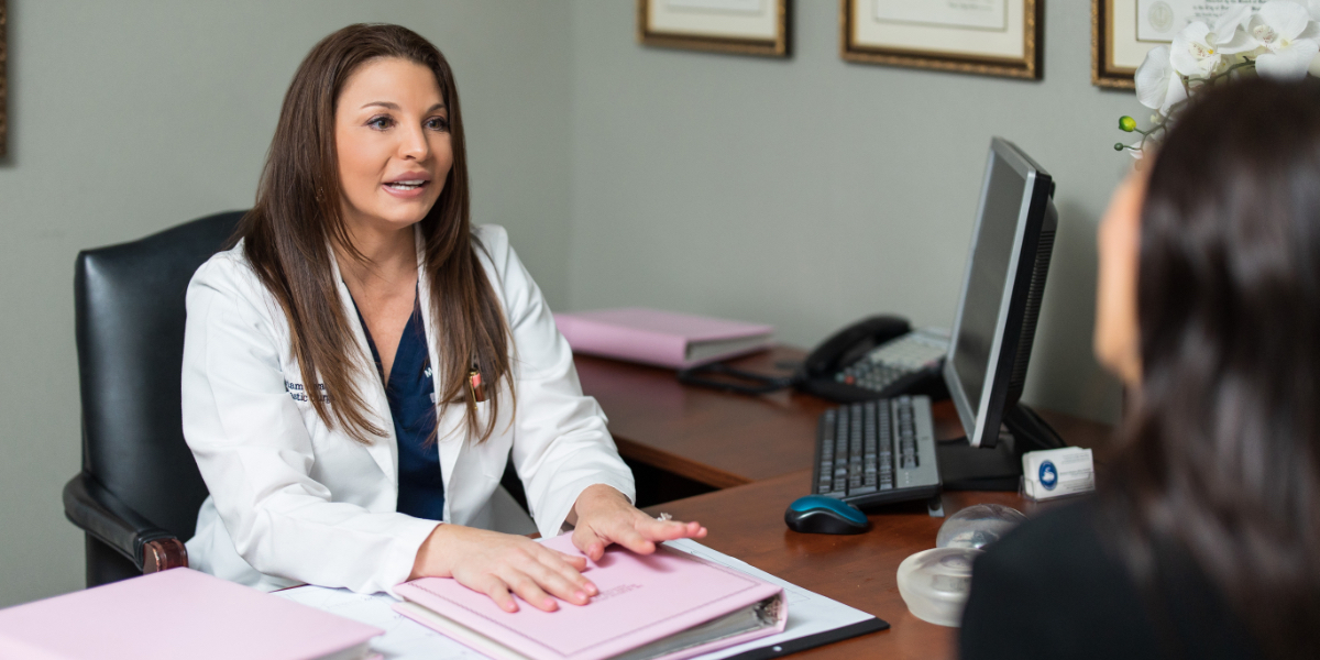 Dr. Awada sitting on her desk with a patient