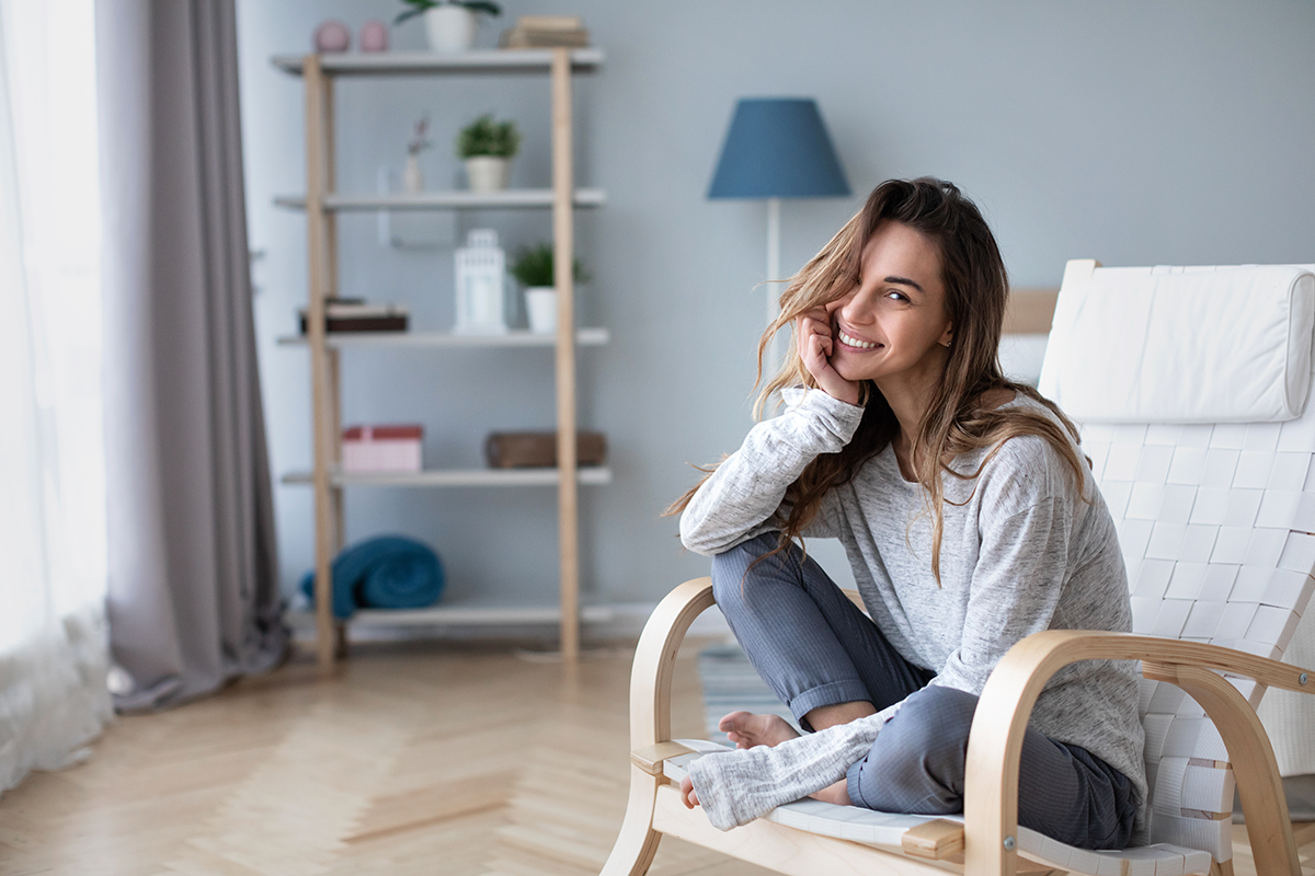 beautiful happy woman looking at camera and smiling while sitting in a cozy chair beautiful happy woman looking at camera and smiling while sitting in a cozy chair