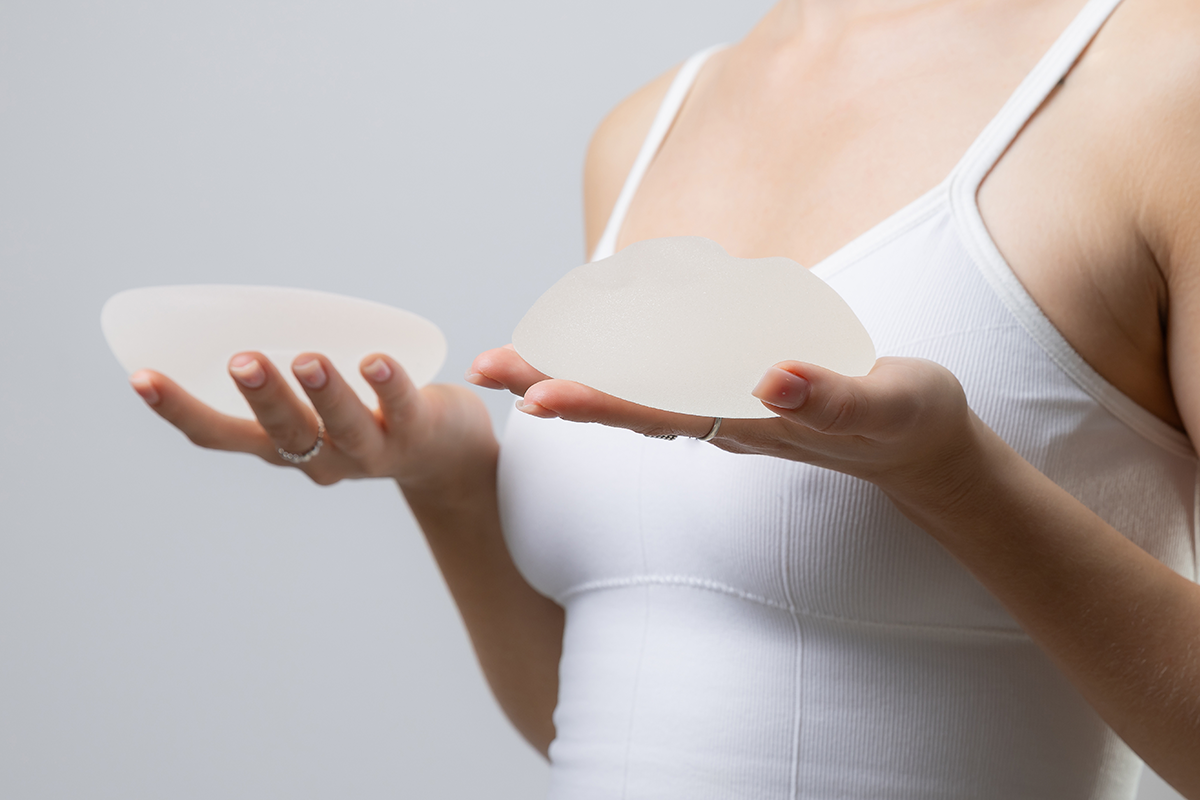 female holding silicone breast implants in each hand for surgical enhancement